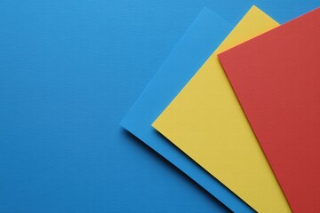 Colorful Sheets of Paper in Blue, Yellow, and Red on Background
