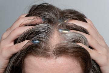 Fingers running through hair with gray strands: A macro shot captures a woman's fingers gently running through her hair, where brown and silvery-gray strands intertwine.