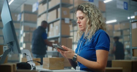 Female logistics manager scans small parcels using smartphone, works in warehouse of postal service. Sorting center employees carrying cardboard boxes for shipping to clients. E-commerce online orders