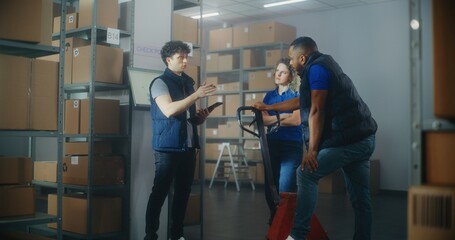 Inventory specialist gives instructions to colleagues, uses tablet computer. Diverse warehouse...