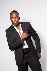Black young businessman in a suit posing in a studio with a white background