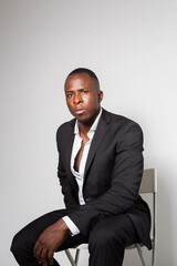 Black young businessman in a suit posing in a studio with a white background