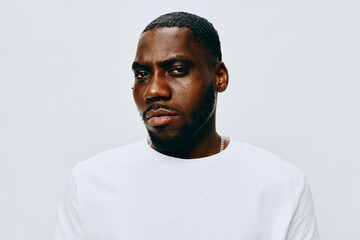 Portrait of a confident man with an intense expression, wearing a white shirt against a light gray background, showcasing strength and attitude in fashion photography