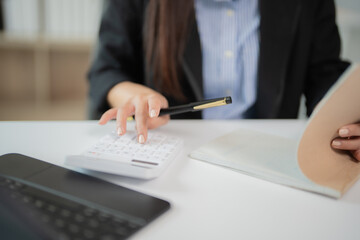 Businesswoman using calculator and holding pen is calculating financial报表, managing household...