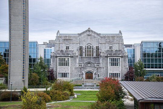 Vancouver, CANADA - Sep 30 2024 : Front view of UBC's Irving K. Barber Learning Centre, featuring Gothic architecture, stone facade, modern glass buildings, and surrounding greenery.