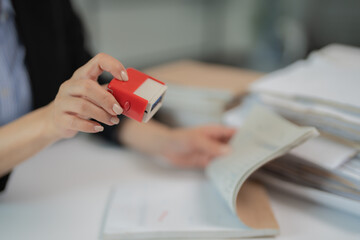 Female hands holding an automatic stamp while browsing through documents, managing paperwork and...