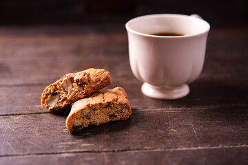 Cantuccini (Italian cookies) and a cup of coffee on dark wooden background. Close up..