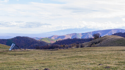 Obraz premium Rural fields with dry grass in the mountains in Romania. Carpathians and cloudy sky in Transylvania, a region in central Romania. Country house on the field for grazing and feeding livestock
