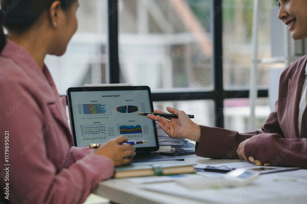 Aufkleber two businesswomen are discussing a summary report displayed on a tablet screen during a meeting in a