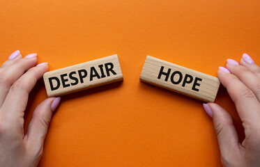 Despair or Hope symbol. Concept word Despair or Hope on wooden blocks. Businessman hand. Beautiful orange background. Business and Despair or Hope concept. Copy space