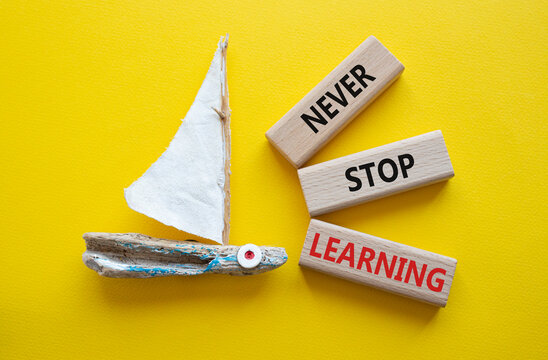 Never stop Learning symbol. Concept words Never stop Learning on wooden blocks. Beautiful yellow background with boat. Business concept and Never stop Learning. Copy space.