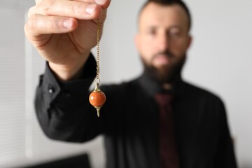 Hypnosis session. Man with pendulum in office, selective focus