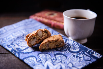 Cantuccini (Italian cookies) and a cup of coffee on dark wooden background. Close up