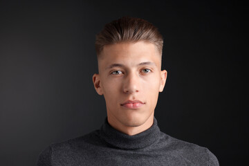 Handsome young man with stylish haircut on black background