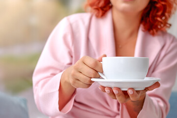 A close-up of a white cup in a woman's hands