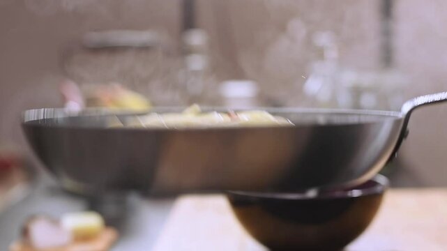 Cooking and stirring the spaghetti with pancetta in the frying pan, close-up in slow motion.
