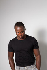 Black man with sculpted gym body wearing a black t-shirt and tartan plaid pants posing in a studio