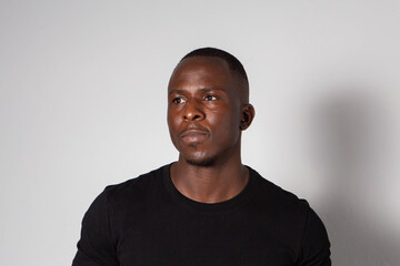 Obraz premium Black man with sculpted gym body wearing a black t-shirt and tartan plaid pants posing in a studio