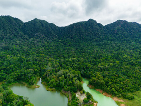 Panoramic aerial drone view of green lake and majestic Singgora mountain range scenery at Tasik Pedu or Pedu Lake in Kuala Nerang, Kedah, Malaysia