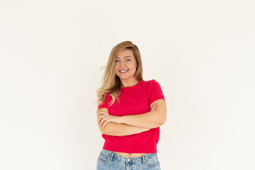 Obraz premium Image of cheerful woman in basic t-shirt smiling at camera while standing with arms crossed isolated over white background