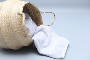 Straw wicker basket and white natural cotton towel laying on gray background. Fashionable bamboo basket. Eco friendly and zero waste item.