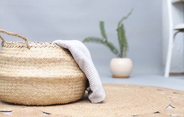 Straw wicker basket and natural cotton towel on handmade jute rug. Stylish interior item. Eco design for bathroom.Space for text.