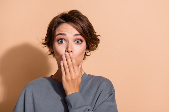 Photo portrait of pretty young girl hand cover mouth shocked face wear trendy gray outfit isolated on beige color background