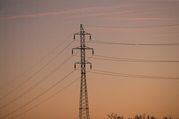 Silhouetted power pole standing tall against a beautiful sunset sky, calm 