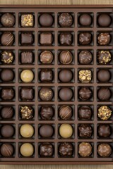 Obraz premium Assorted gourmet chocolate truffles and bonbons in a wooden box, perfect for gifting or a special occasion.