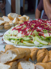 Plate of salad with cucumber, lettuce and shredded beetroot with a plate of bread slices on the side as a Christmas dinner. Verical