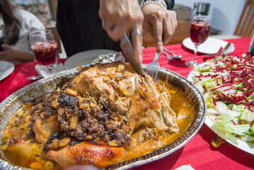 Woman's hands cutting stuffed turkey on a table for Christmas dinner in a Mexican family.
