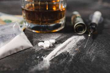 White drugs, narcotic pills, an alcoholic drink in a glass, a syringe with a dose of heroin, a line...