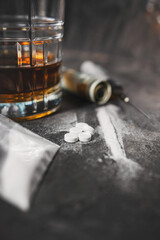 White narcotic pills, an alcoholic drink in a glass, a syringe with a dose of heroin, a line of...