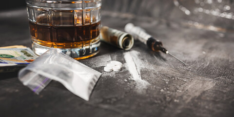 White narcotic pills, an alcoholic drink in a glass, a syringe with a dose of heroin, a line of...