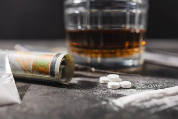 White drugs, narcotic pills, an alcoholic drink in a glass, a syringe with a dose of heroin, a line...