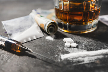 White drugs, narcotic pills, an alcoholic drink in a glass, a syringe with a dose of heroin, a line...