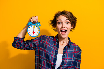Portrait of astonished ecstatic girl with bob hairstyle wear checkered shirt hold alarm staring...