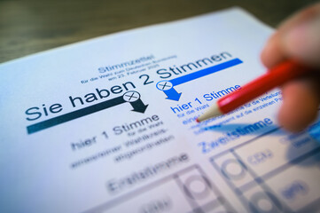 Stimmzettel zur Bundestagswahl und Hand die einen roten Stift hält