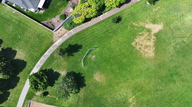 Ascending and rotating aerial view above an empty baseball and softball field in a city park.