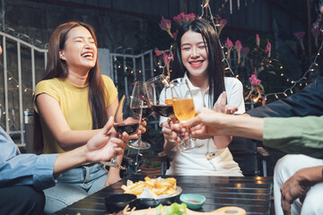 Cheers to Friendship:  A group of young friends raise their glasses in a toast, laughing and enjoying each other's company at a cozy outdoor gathering.