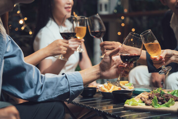 Nighttime Cheers: Friends raise a toast, enjoying delicious food and drinks at a lively outdoor gathering. The warm lighting and intimate setting create a feeling of camaraderie and celebration. 