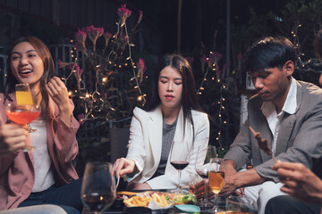 Nightlife Gathering: Friends enjoying drinks and appetizers at a dimly lit outdoor venue.  The scene is warm, inviting, and full of casual conversation.