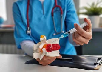 Neurologist doctor holds imitation of spine with intervertebral hernia