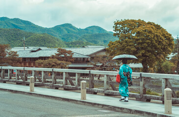 Picturesque scene with a woman holding an umbrella and wearing a traditional japanese kimono on the...