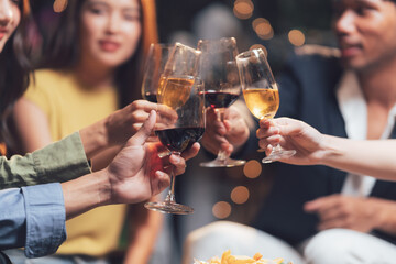 Friends Cheers: A toast to friendship and good times. Close-up shot of diverse group of friends raising their wine glasses in a celebratory toast at a cozy gathering.