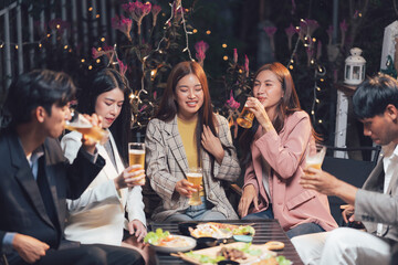 Nighttime Celebration: A group of friends raise their glasses in a toast, enjoying drinks and conversation under the twinkling lights of an outdoor bar.