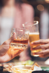 Cheers to Friendship: Hands clinking glasses of whiskey and beer, a toast to camaraderie and good times. Close up, warm tones, selective focus.  