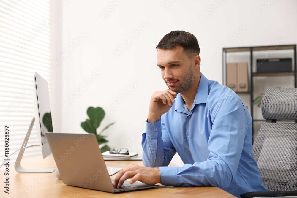 Poster programmer working on laptop at wooden desk indoors