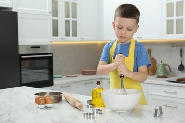 Little helper. Cute boy making dough for cookies in kitchen at home, space for text