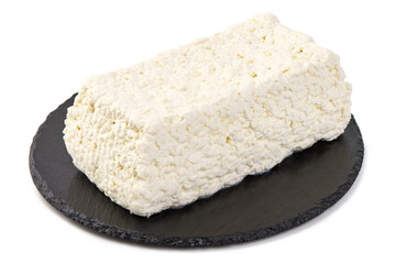 Fresh block of cottage cheese on a black slate plate, isolated on white background.